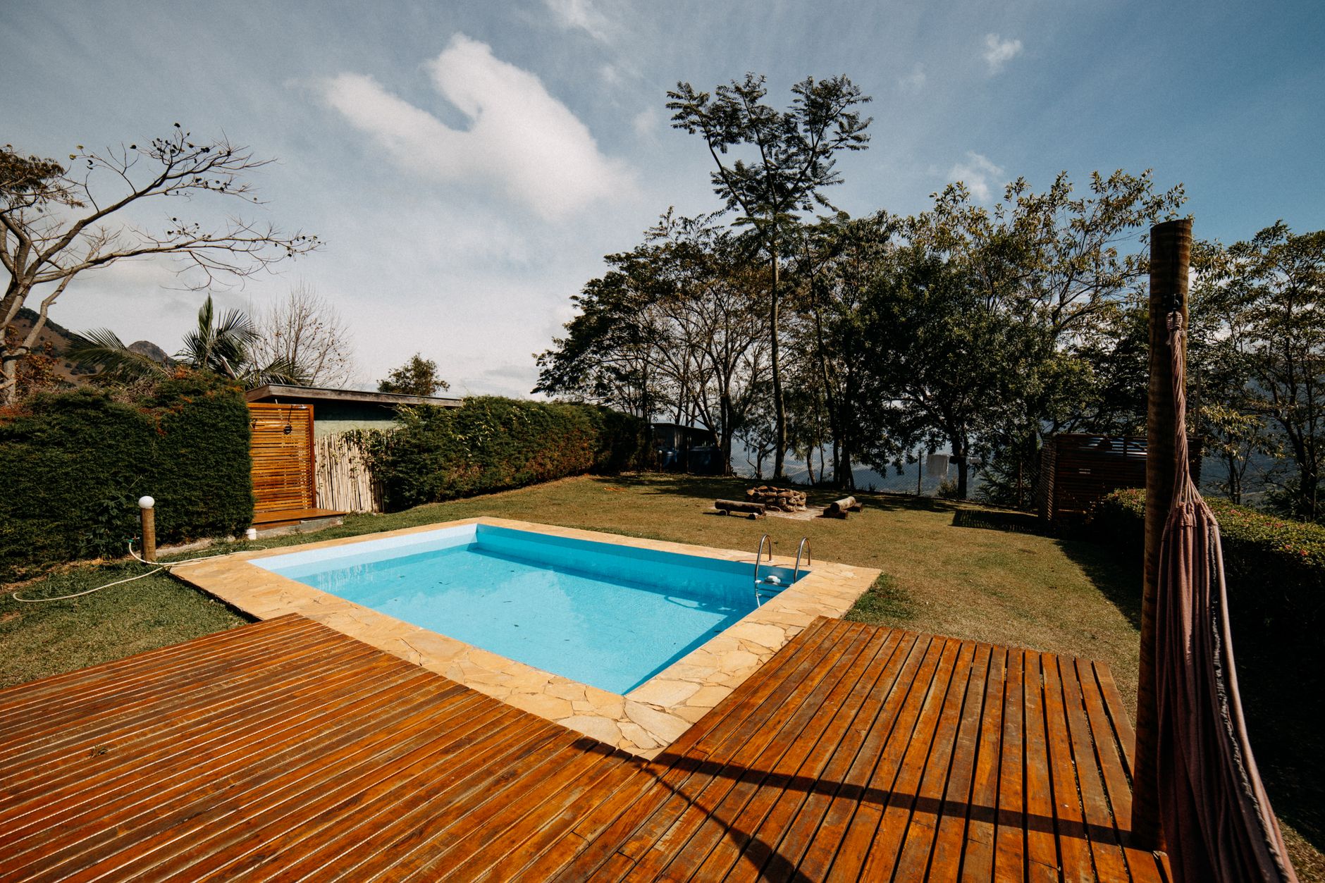 Scenic outdoor swimming pool surrounded by lush greenery and wooden decking, ideal for relaxation.