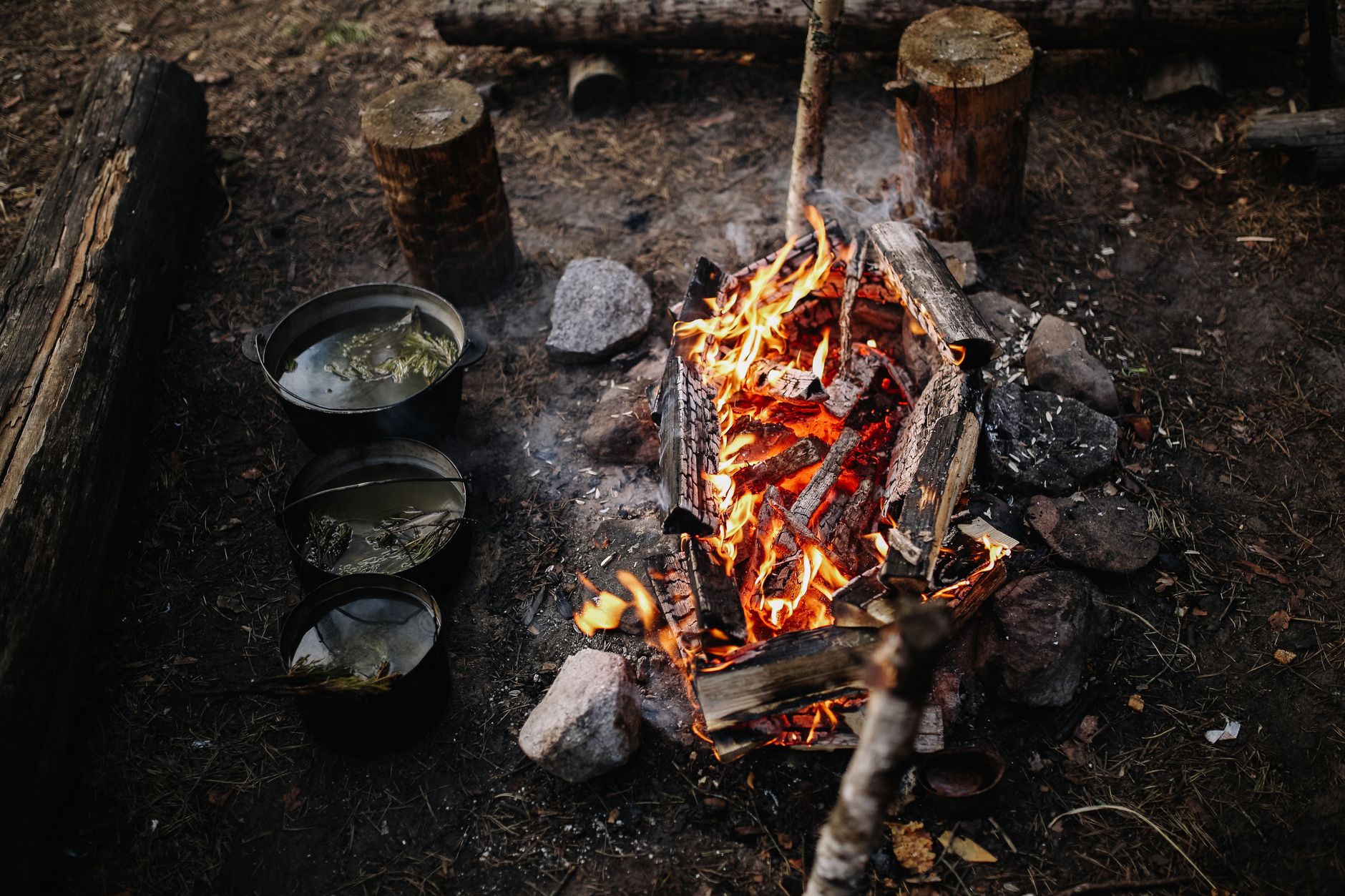A cozy campfire with pots cooking in a rustic outdoor setting, perfect for wilderness adventures.