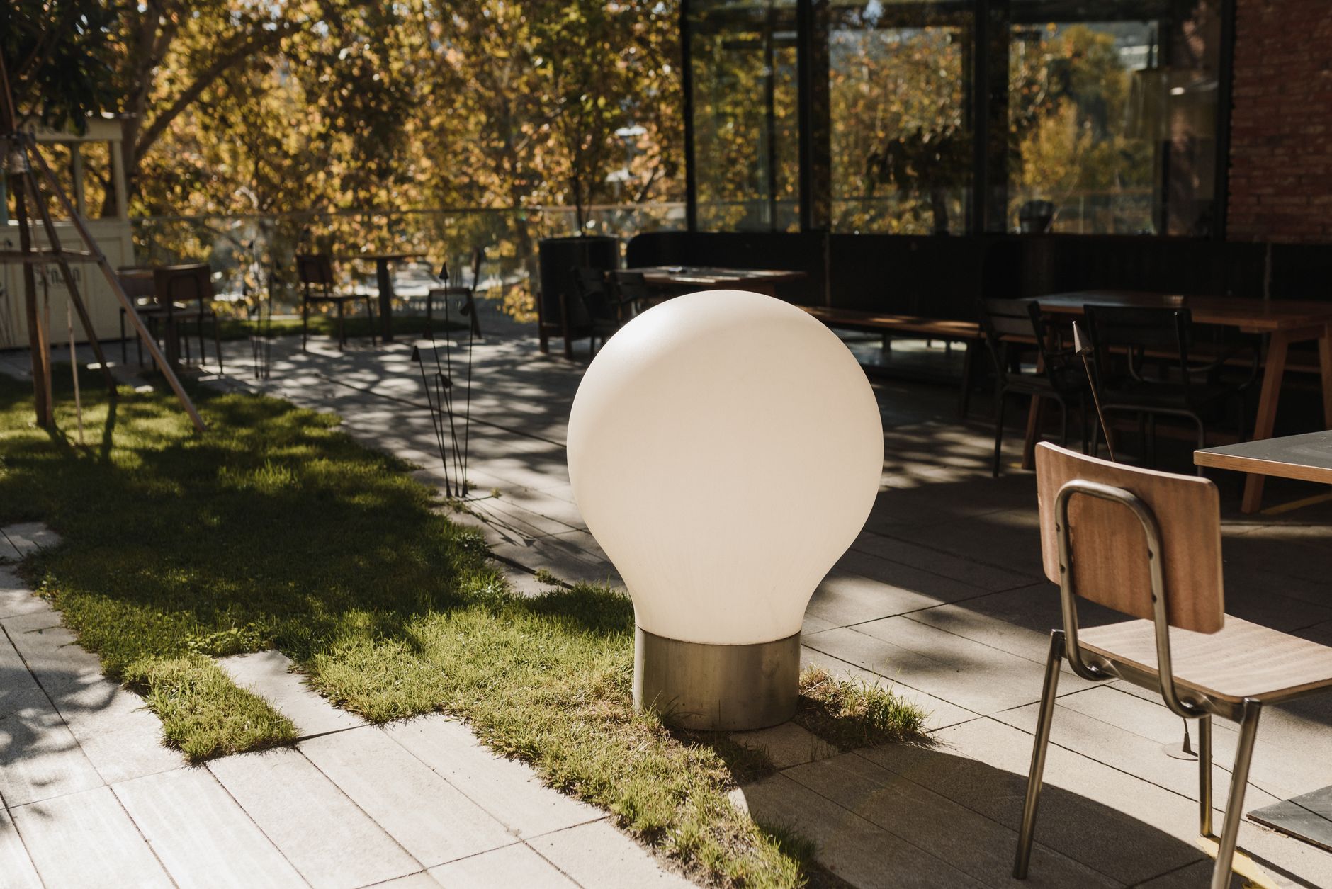 A stylish outdoor dining area featuring a spherical lamp and modern furniture under natural daylight.