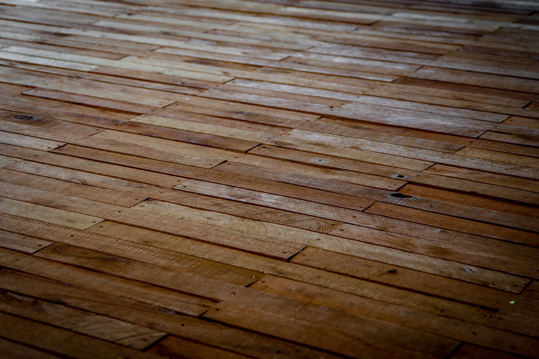 Detailed view of rustic wooden floor with staggered planks showcasing natural texture.